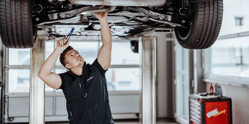 In unserem Autohaus in Melk bieten wir ab sofort eine berufliche Chance als KFZ-Techniker - gleich jetzt bewerben! Am Bild: Techniker, welcher ein Auto von unten besichtigt